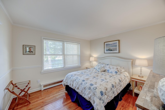 bedroom with a baseboard radiator, crown molding, light wood finished floors, and baseboards