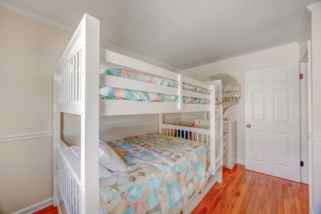 bedroom with wood finished floors, crown molding, and baseboards