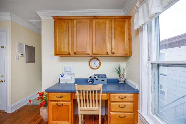 office space featuring ornamental molding, built in desk, electric panel, and dark hardwood / wood-style flooring