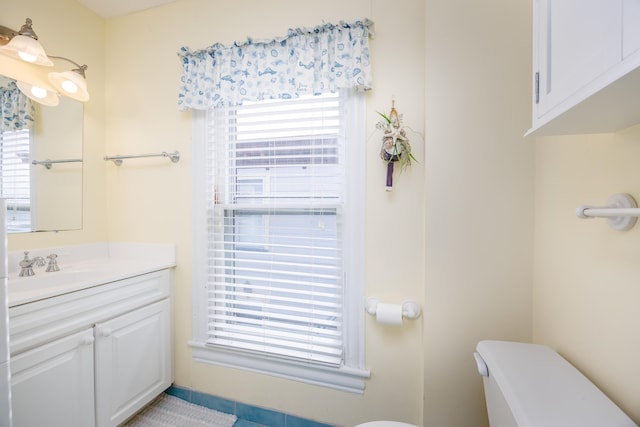 bathroom featuring vanity, plenty of natural light, and toilet