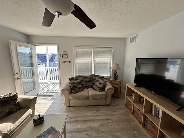 living room featuring a textured ceiling, light hardwood / wood-style flooring, and ceiling fan