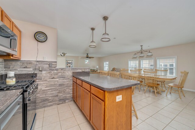 227 E Leaming Ave Unit A, Wildwood, NJ 08260 - kitchen featuring appliances with stainless steel finishes, light tile patterned floors, a kitchen bar, dark countertops, and a ceiling fan