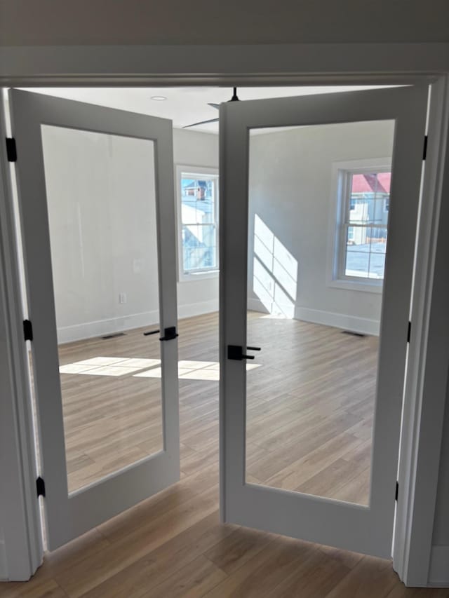 empty room with french doors, plenty of natural light, and light hardwood / wood-style floors