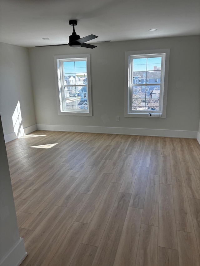 empty room with ceiling fan, a healthy amount of sunlight, and light wood-type flooring