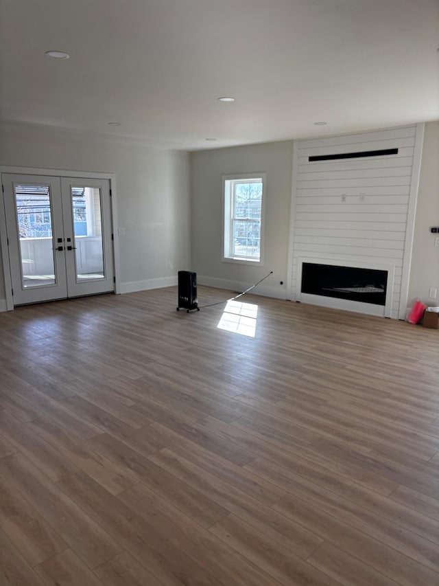 unfurnished living room featuring wood-type flooring, a fireplace, and french doors