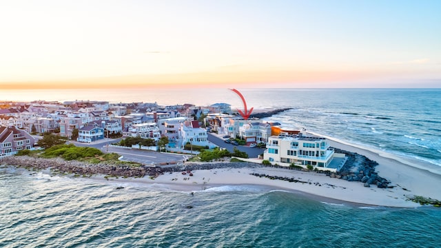 aerial view at dusk featuring a beach view and a water view