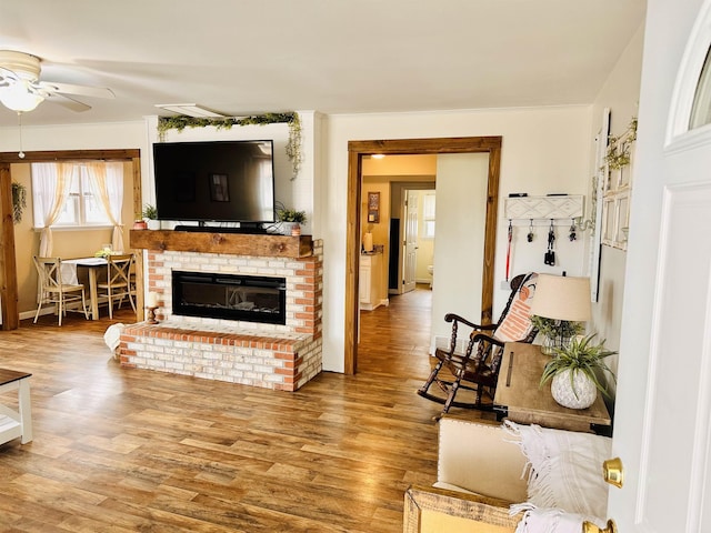 living area with a fireplace, wood finished floors, and a ceiling fan