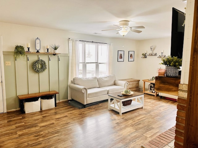 living area with visible vents, wood finished floors, and ceiling fan