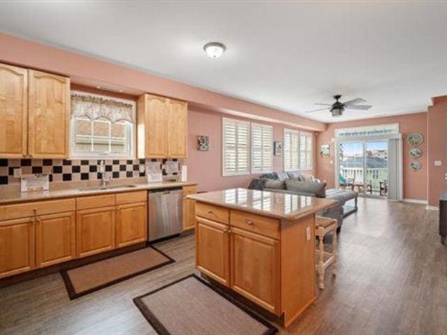 kitchen featuring sink, dishwasher, a kitchen island, hardwood / wood-style floors, and decorative backsplash