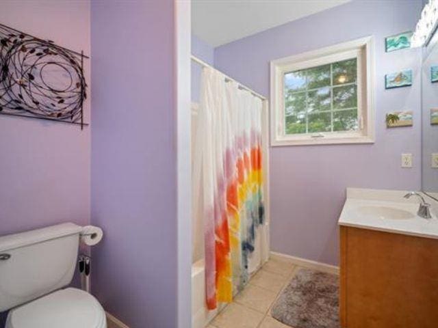 full bathroom featuring tile patterned floors, vanity, toilet, and shower / bath combo with shower curtain