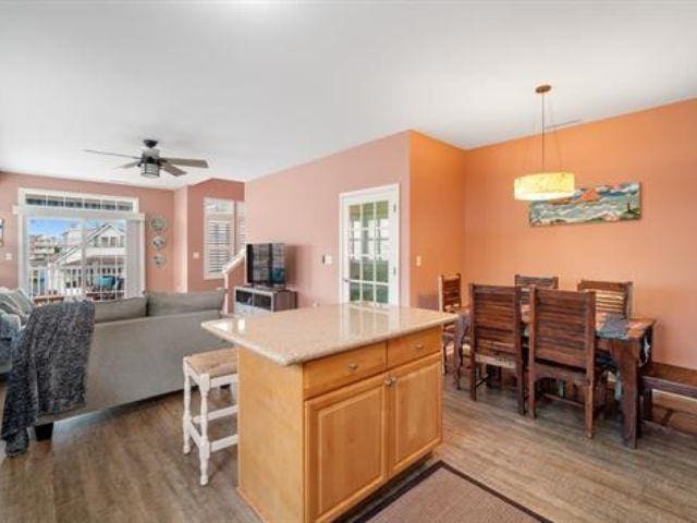 kitchen featuring a center island, hanging light fixtures, a kitchen breakfast bar, dark hardwood / wood-style floors, and ceiling fan