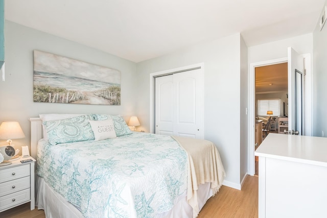 bedroom featuring a closet, light wood-type flooring, and baseboards