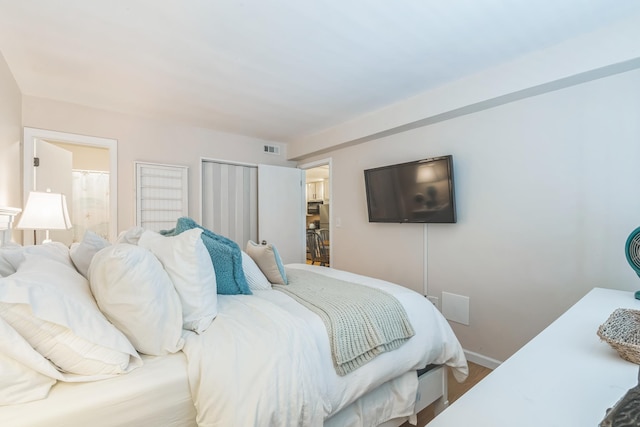 bedroom featuring baseboards, wood finished floors, and ensuite bathroom