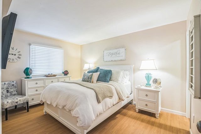 bedroom with light wood finished floors and baseboards