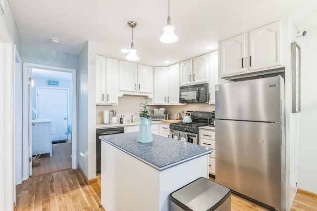 kitchen featuring appliances with stainless steel finishes, light wood-type flooring, white cabinetry, hanging light fixtures, and a kitchen island