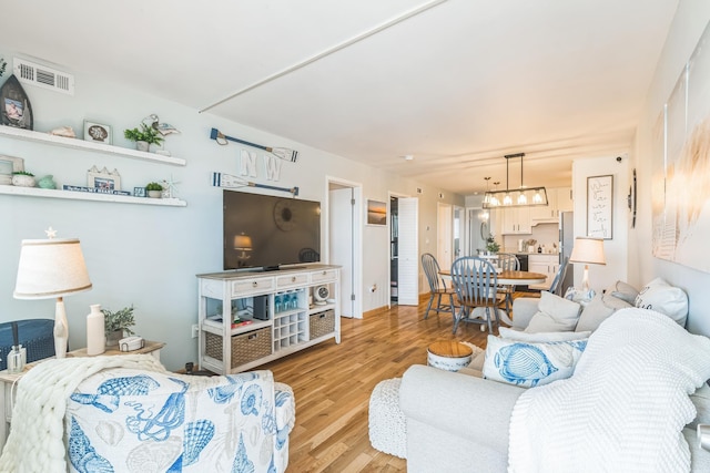 living room with light wood-style floors and a chandelier