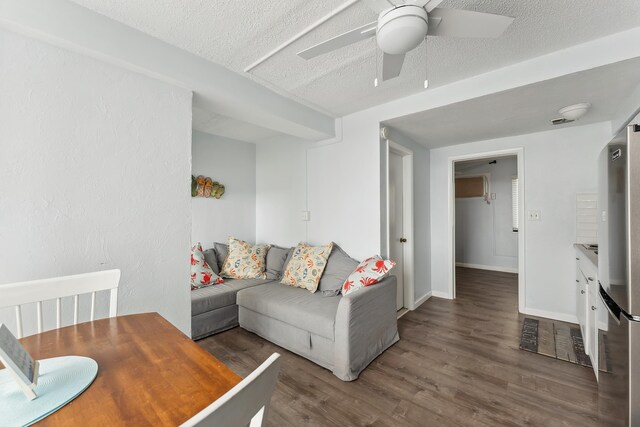 living area featuring ceiling fan, a textured ceiling, baseboards, and wood finished floors