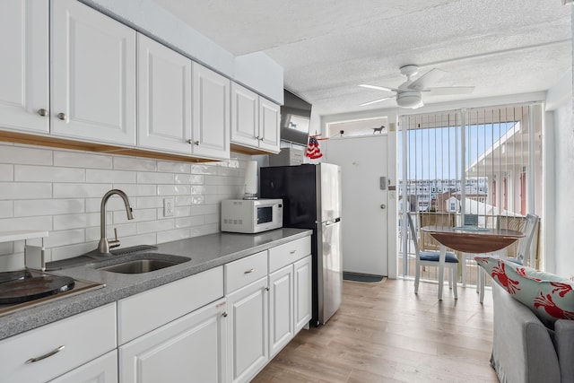 kitchen featuring white microwave, ceiling fan, light wood-style flooring, white cabinetry, and a sink