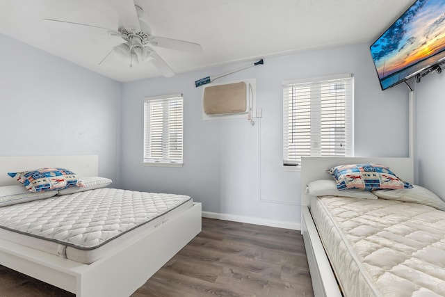 bedroom featuring a wall mounted air conditioner, baseboards, dark wood-type flooring, and a ceiling fan