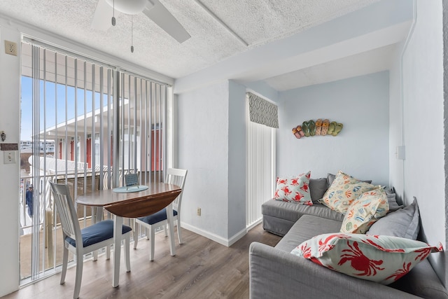 dining room featuring ceiling fan, wood finished floors, baseboards, and a textured ceiling