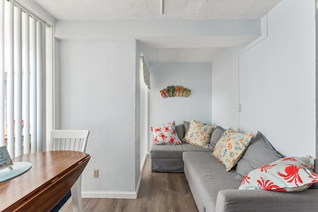 living area featuring baseboards, a textured ceiling, and wood finished floors