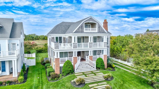 view of front facade with a porch, a balcony, and a front yard