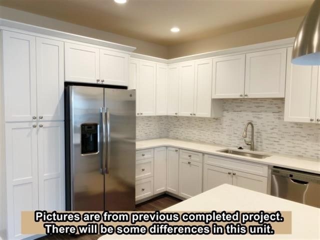 kitchen featuring tasteful backsplash, sink, white cabinets, and stainless steel appliances