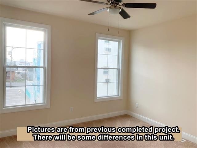 carpeted empty room with ceiling fan and plenty of natural light