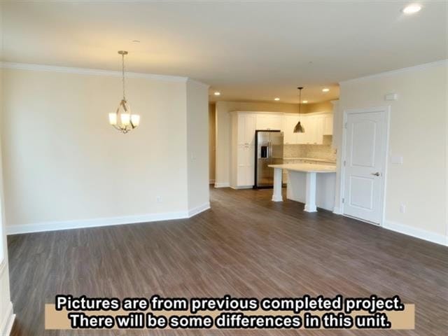 unfurnished living room featuring dark hardwood / wood-style flooring, an inviting chandelier, and ornamental molding