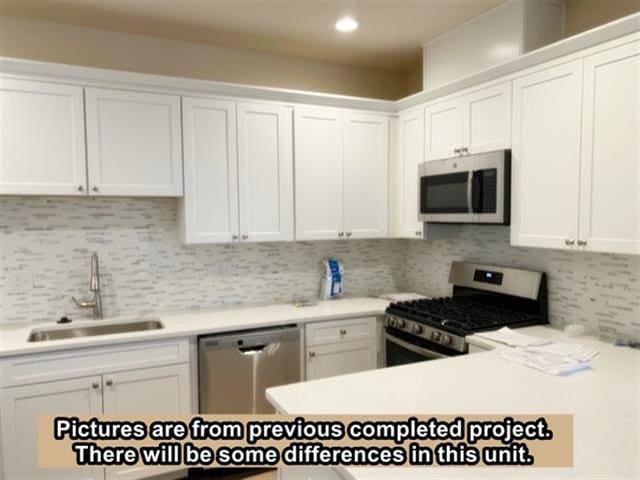 kitchen featuring white cabinets, appliances with stainless steel finishes, tasteful backsplash, and sink