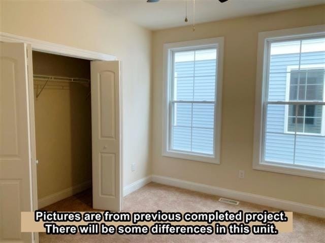 unfurnished bedroom with multiple windows, a closet, and light colored carpet