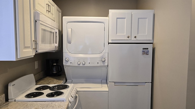 kitchen with white appliances, white cabinets, and stacked washing maching and dryer