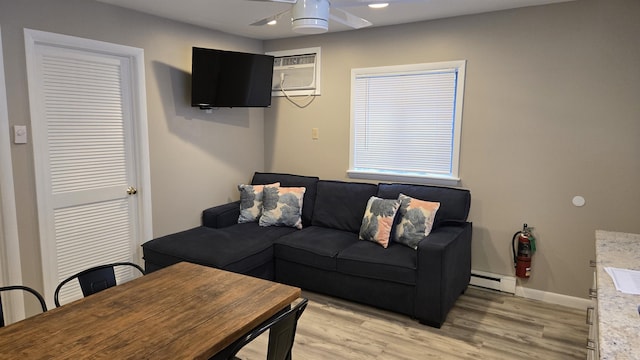 living room with a baseboard heating unit, light hardwood / wood-style flooring, an AC wall unit, and ceiling fan