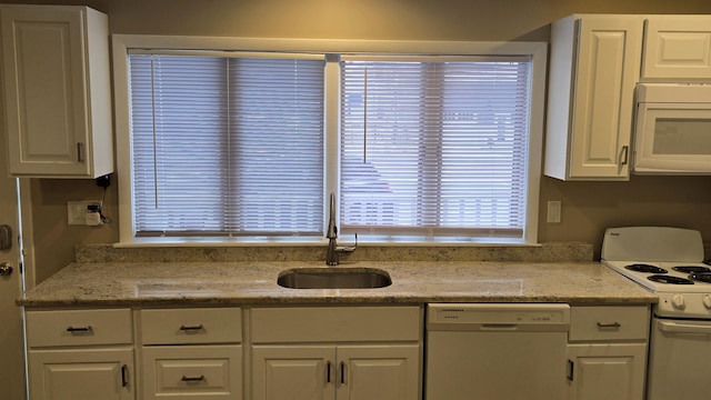 kitchen with sink, light stone counters, white cabinets, and white appliances