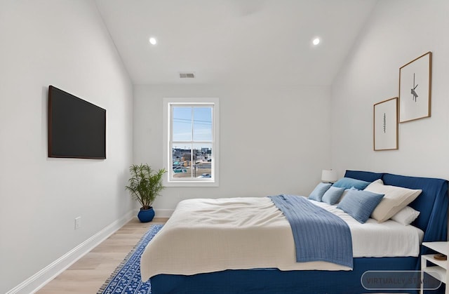 bedroom featuring lofted ceiling, light wood-style flooring, visible vents, and baseboards