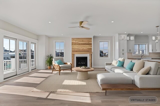 living room with ceiling fan, light wood-style flooring, recessed lighting, a fireplace, and baseboards