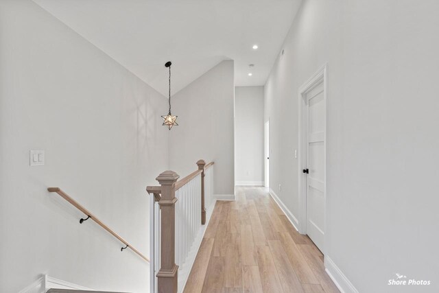 hallway with recessed lighting, an upstairs landing, baseboards, vaulted ceiling, and light wood-type flooring