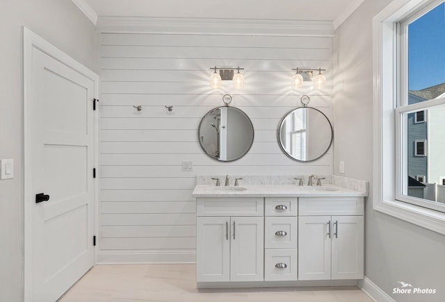 bathroom featuring double vanity, baseboards, ornamental molding, and a sink