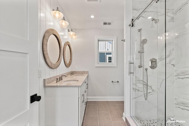 full bathroom with baseboards, a sink, and a marble finish shower