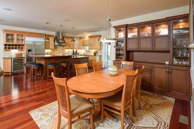 dining room featuring crown molding, dark wood-type flooring, and beverage cooler