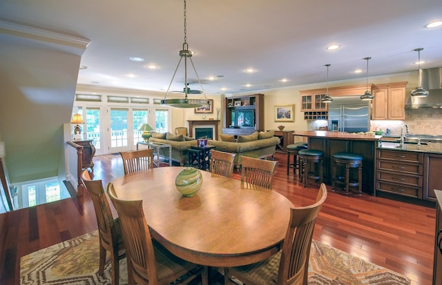 dining area with crown molding, dark hardwood / wood-style flooring, french doors, and sink