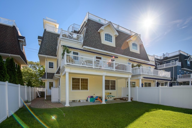 back of property featuring a yard, a patio area, and a balcony