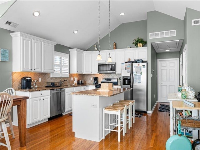 kitchen featuring a center island, white cabinetry, appliances with stainless steel finishes, and tasteful backsplash