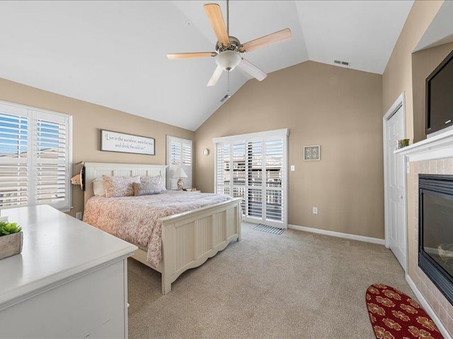 carpeted bedroom featuring a tiled fireplace, ceiling fan, vaulted ceiling, and access to exterior