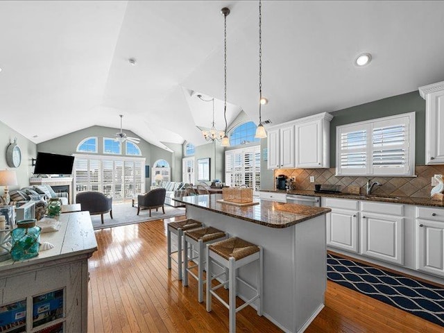 kitchen with white cabinets, decorative light fixtures, backsplash, and a center island