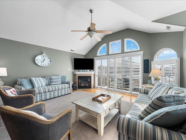 living room with ceiling fan, a fireplace, and vaulted ceiling