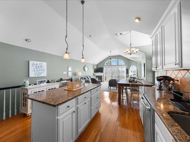 kitchen featuring pendant lighting, dishwasher, a center island, white cabinets, and vaulted ceiling