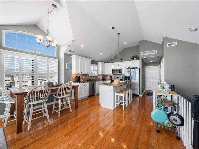 kitchen with decorative backsplash, a kitchen breakfast bar, stainless steel appliances, white cabinetry, and a kitchen island