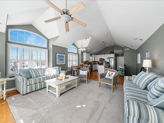 living room featuring vaulted ceiling, hardwood / wood-style floors, and ceiling fan with notable chandelier