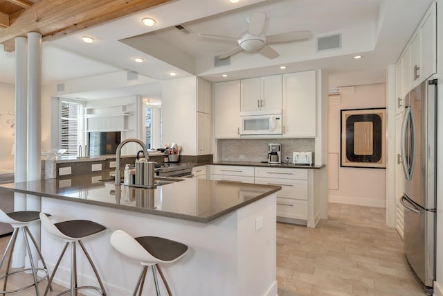 312 S Lake Dr, Cape May Point, NJ 08212 - kitchen featuring freestanding refrigerator, white microwave, backsplash, a kitchen bar, and white cabinetry
